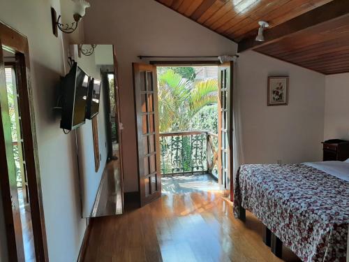 a bedroom with a bed and a door to a balcony at Pousada Imperial Koeler in Petrópolis