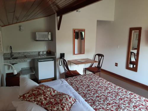 a bedroom with a bed and a desk and a table at Pousada Imperial Koeler in Petrópolis