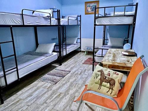 a room with three bunk beds with a table and a chair at Tbil Home Hostel in Tbilisi City