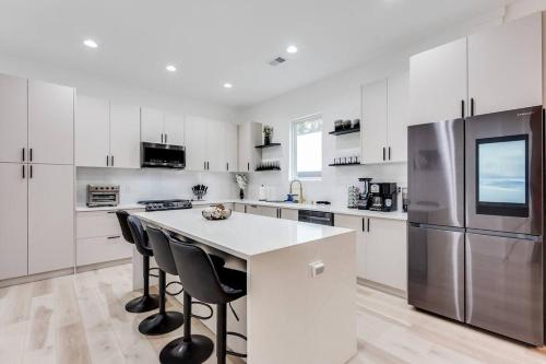 a white kitchen with a refrigerator and a counter with chairs at Modern Luxury In The City at Havilah Estates in Atlanta
