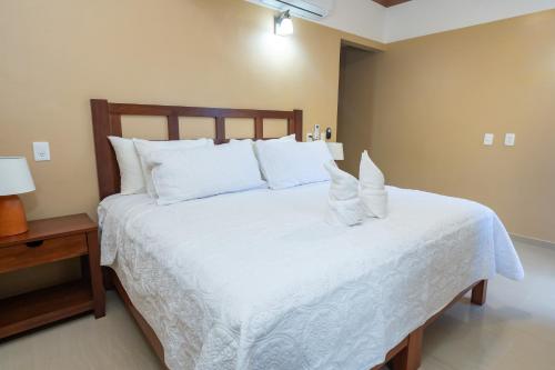 a bedroom with a bed with white sheets and pillows at The Garden Hotel in Palenque