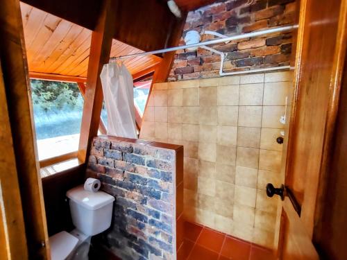 a bathroom with a toilet and a stone wall at Refugio Génesis habitaciones Lago de Tota in Tota