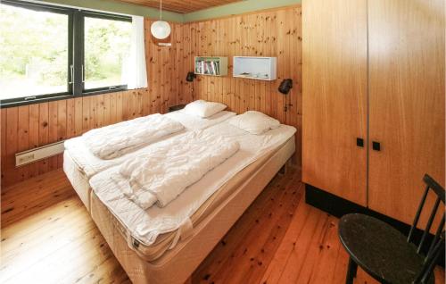 1 dormitorio con 1 cama grande en una pared de madera en Stunning Home In Sams With Kitchen, en Nordby