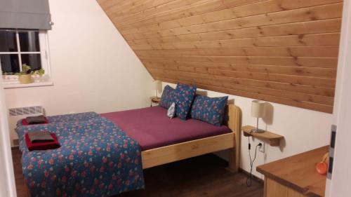 um pequeno quarto com uma cama e um tecto em madeira em Chaloupka pod Kančí stezkou em Nova Ves nad Nisou