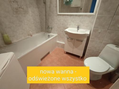 łazienka z białą toaletą, umywalką i wanną w obiekcie Green Kabaty Apartment 1 w Warszawie