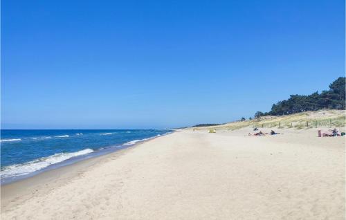 a beach with people sitting on the sand and the ocean at Nice Home In Postomino With Sauna in Postomino