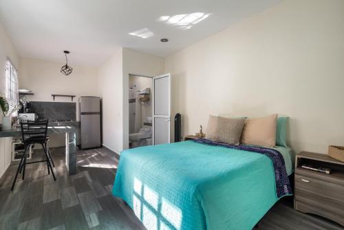 a bedroom with a bed and a desk and a kitchen at El depa de Acuario in Cancún