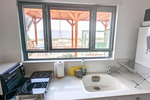 eine Küchentheke mit einem Waschbecken und einem Fenster in der Unterkunft Charming unit in Dead Sea in Ovnat