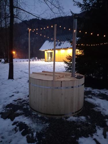 a wooden tub in the snow in front of a house at Mała Gorczańska Chatka in Ochotnica Dolna