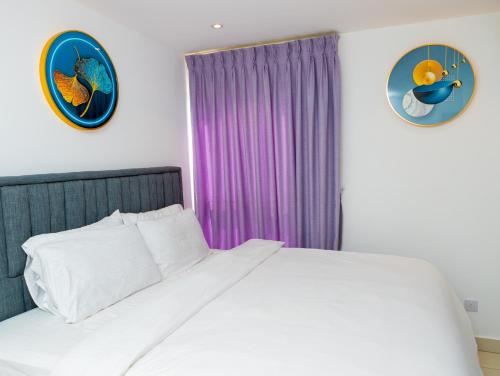 1 dormitorio con cama blanca y cortinas moradas en Piano and Gold at The Lennox, Airport Residential en Accra