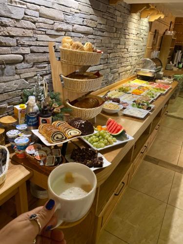 a person holding a cup of coffee next to a buffet of food at Leśne Apartamenty in Białka Tatrzanska