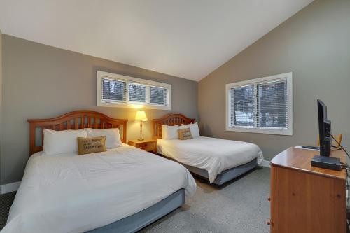 a bedroom with two beds and a tv and two windows at 728 Disciples Village Condo in Boyne Falls