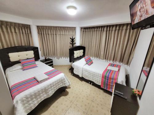 a bedroom with two beds and a window with curtains at Hostal EL VIAJERO en Ollantaytambo in Ollantaytambo