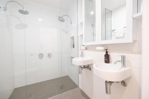 a white bathroom with a sink and a shower at Swell Byron Bay - Opposite the Belongil Beach in Byron Bay