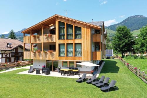 a large wooden house with a deck and chairs at Mas dei Masi in Cavalese