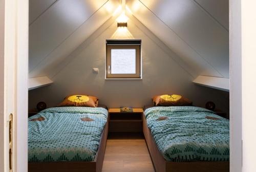 a attic room with two beds and a window at Casa di Luna in Middelkerke