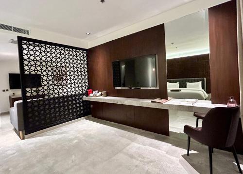 Tajreed Suites في الرياض: غرفة في الفندق بها مكتب استقبال وتلفزيون