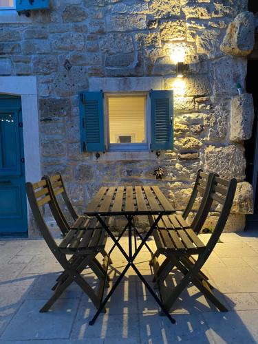 a wooden table and two chairs in front of a building at MINIQ HOMES 102 - Historical Stone House with Garden Cinema in Foca