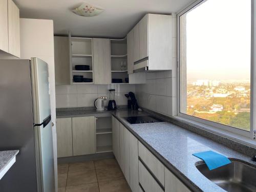 a kitchen with white cabinets and a large window at Condominio Costa Peñuelas in Coquimbo