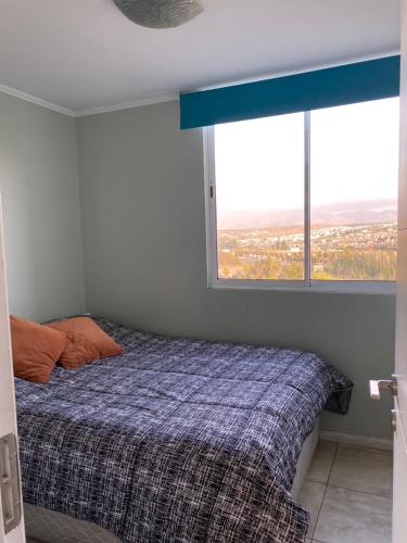 a bedroom with a bed and a large window at Condominio Costa Peñuelas in Coquimbo