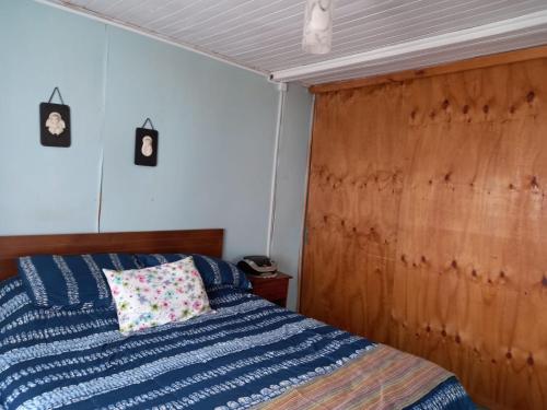 1 dormitorio con cama azul y cabecero de madera en linda casa de campo, en Futrono