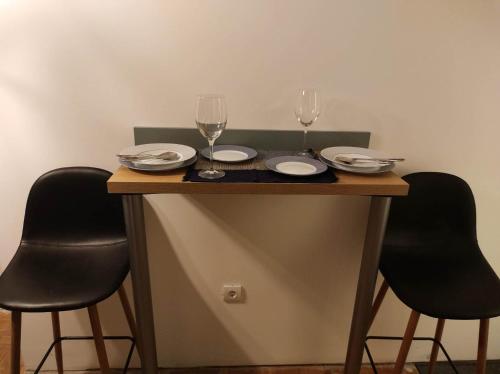 a table with two wine glasses and plates on it at Studio Sunset in Voždovac