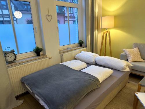 uma cama num quarto com duas janelas em Stilvolle, charmante Ferienwohnung in Plauen em Plauen