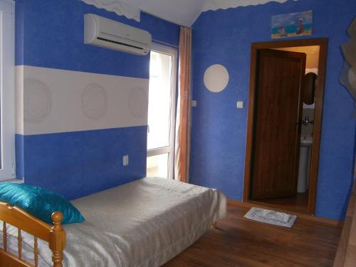 a blue bedroom with a bed and a window at Morska Zvezda Guest house in Pomorie