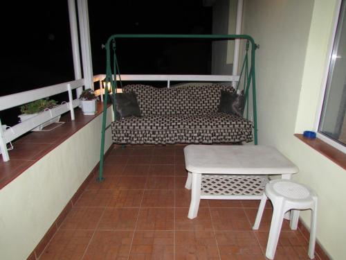 a balcony with a couch and a table and stool at Morska Zvezda Guest house in Pomorie