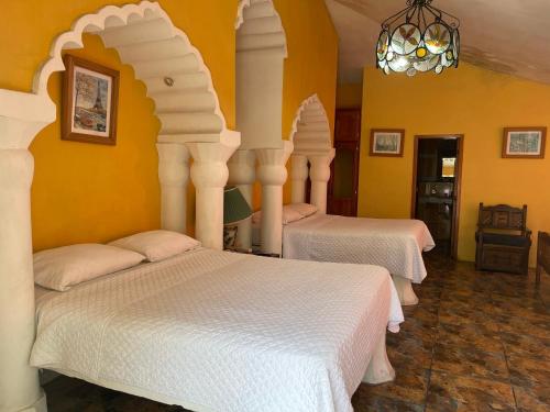 2 camas en una habitación con paredes amarillas en Club Samawa, en Santo Domingo de los Colorados