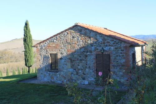 a stone building with a door in a field at Agriturismo Ragoncino in Laiatico