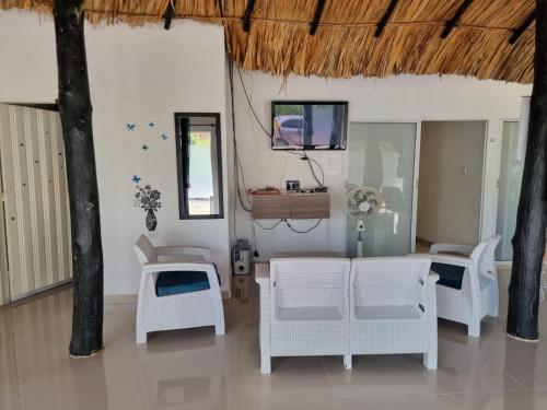 ein Wohnzimmer mit weißen Stühlen und einem TV in der Unterkunft PLAYABRISAMAR in San Antero