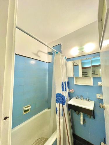 baño azul con ducha y lavamanos en Departamento Excelente Ubicacion en Mar del Plata