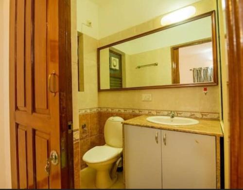 a bathroom with a toilet and a sink and a mirror at Dona Paula Apartment in Dona Paula