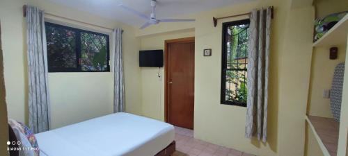 a bedroom with a bed and two windows at Casa Hadassa La Cañada in Palenque