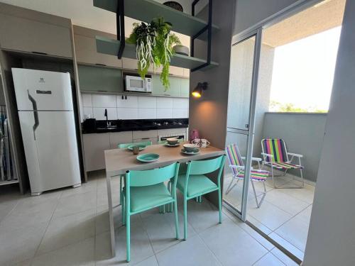 a kitchen with a table and chairs and a refrigerator at Apê Encantador em Piçarras in Piçarras