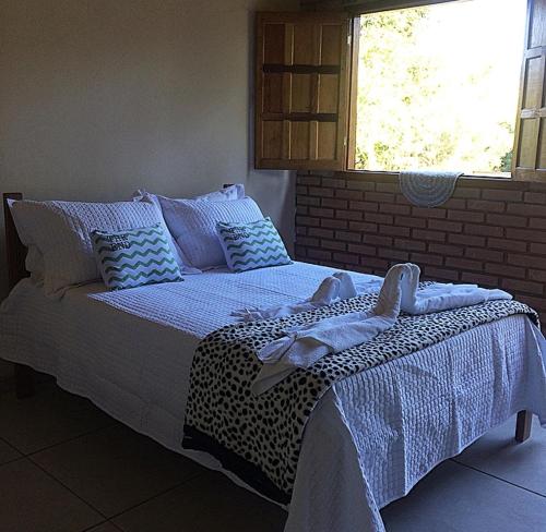ein Bett mit blauer und weißer Bettwäsche und einem Fenster in der Unterkunft Pousada Rural e Pesqueiro Chalé da serra in Conceição da Ibitipoca