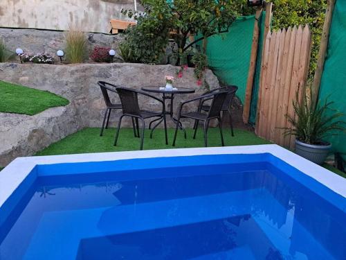 a table and chairs next to a blue swimming pool at Casa Vista del sol, con piscina, tinaja, y quincho in Caracha