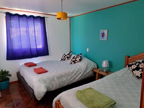 2 camas en una habitación con paredes azules en Casa Vista del sol, con piscina, tinaja, y quincho, 