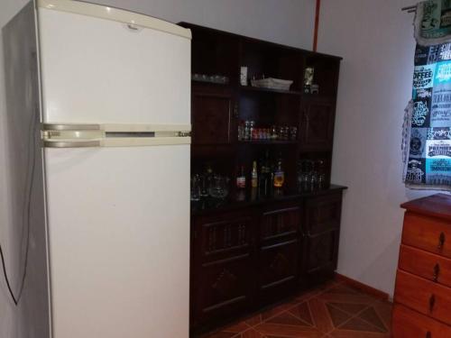 a kitchen with a refrigerator and a shelf with alcohol bottles at Casa Vista del sol, con piscina, tinaja, y quincho in Caracha