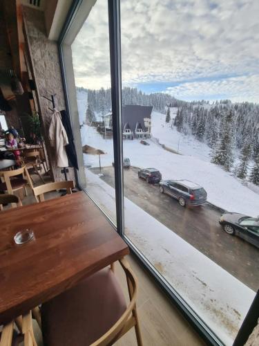 a window with a table and a view of a snowy street at Apartman Drvorez-direktno na ski stazi in Jahorina