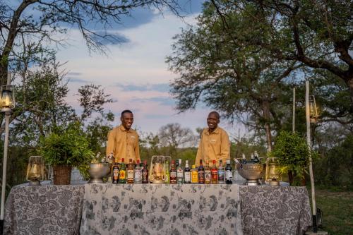 two men standing in front of a table with drinks at Thornybush Game Lodge in Thornybush Game Reserve