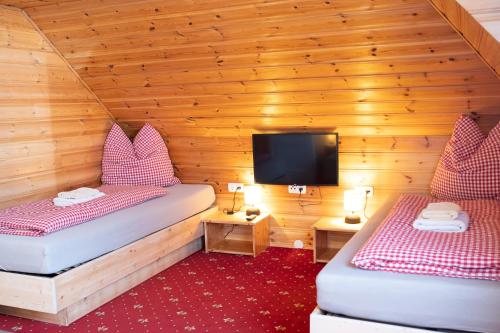 Habitación con 2 camas y TV en una cabaña en Rösslgut Bed & Breakfast, en Zederhaus