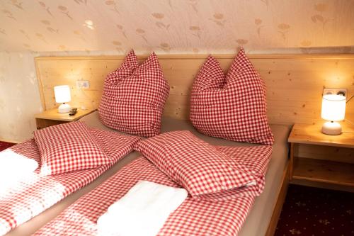 a bed with four red and white pillows on it at Rösslgut Bed & Breakfast in Zederhaus