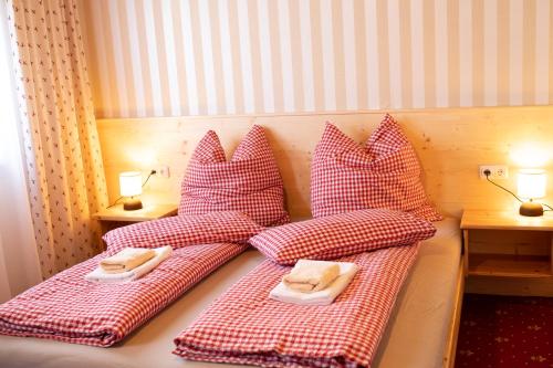 a bed with red and white pillows on it at Rösslgut Bed & Breakfast in Zederhaus