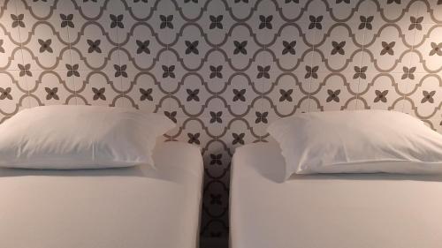 a bed with two pillows and a wall stenciled at A Casa do Tenente in Faro