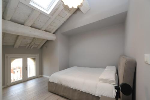 a white bedroom with a bed and a window at Loggia del Tenore Suite in Modena