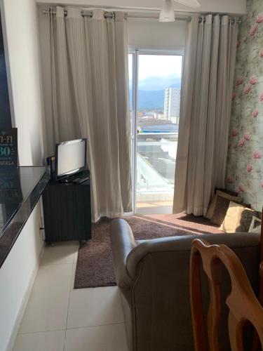 a living room with a couch and a large window at Espaço Mahina - Unidade Dez - Apartamento para temporada Praia Grande Ocian in Praia Grande