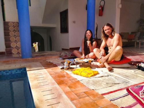 dos personas sentadas en el suelo junto a una piscina en Tigmi surf morocco, en Tiguemmi nʼAït Bihi