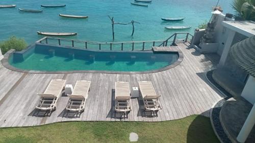 una terraza con sillas y una piscina junto al agua en Ceningan Beachside Villas en Lembongan